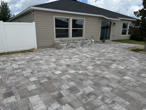 Wide backyard patio in a light grey blend stretching from an Ocala home's sliding door to the vinyl fence