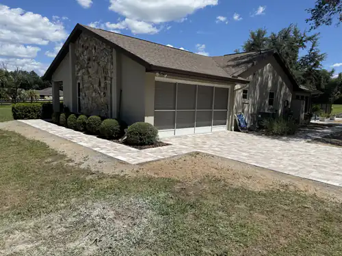 Driveway turning into a front walkway beside a stone accent wall
