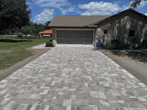 Long blended paver driveway leading to a screened side garage under large oak trees in Ocala