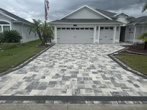 Straight on view of the flared navy and white paver driveway with a charcoal edge band