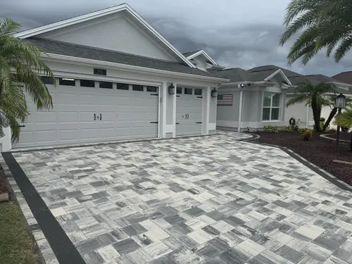 Blue grey paver blend in front of a double and single garage with palms beside the drive