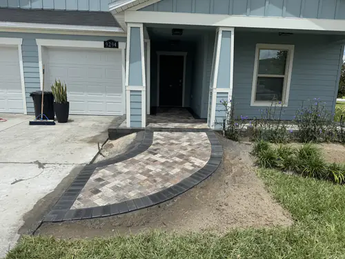 Front porch of a blue sided Ocala home with a new curved paver landing off the concrete driveway
