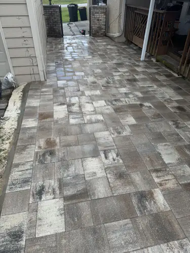 Wet large paver side alley running to a gate and trash cans at an Ocala home