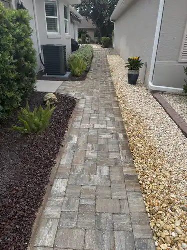 Blended tan and grey pavers leading along an Ocala side yard past the air conditioner