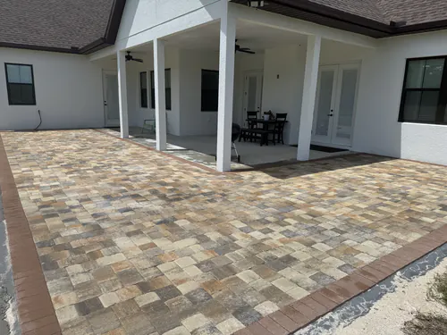 Tan, gold and brown paver patio with a red brown border stretching past an Ocala lanai