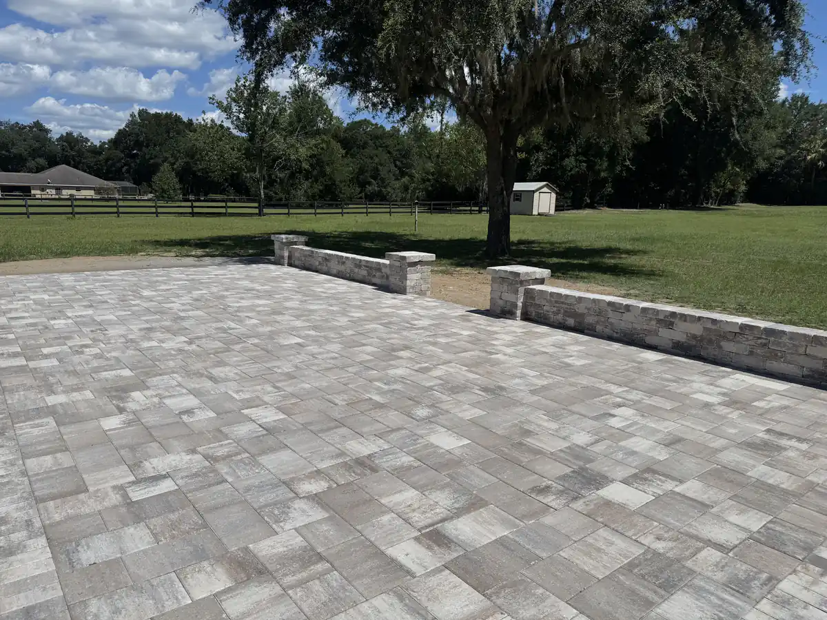 Large backyard paver patio edged with low capped seat walls and pillars looking out over an Ocala pasture