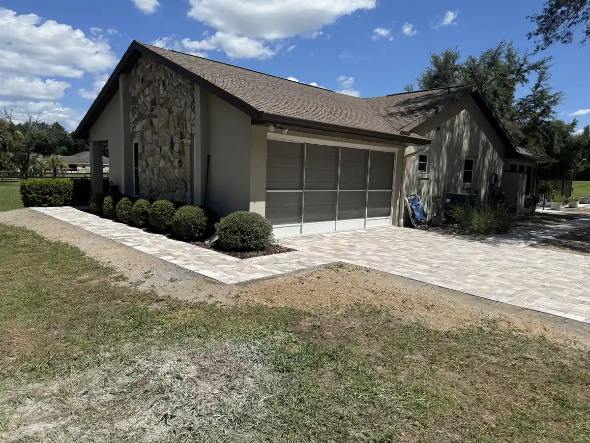 Blended paver driveway wrapping into a walkway along the front of a stone accented Ocala home with shrubs