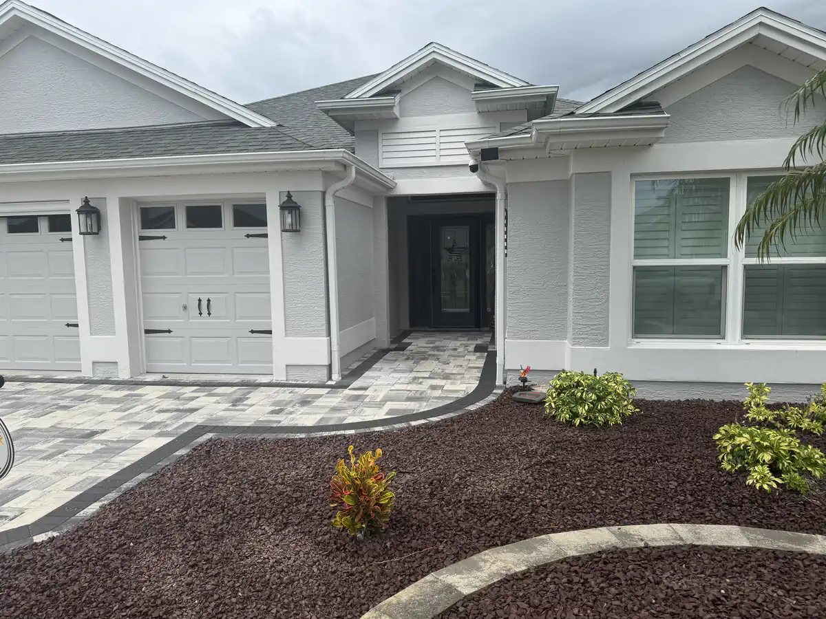 Paver walkway with a charcoal border curving to the front entry past red mulch beds in The Villages