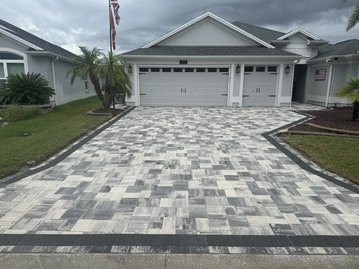 Straight on view of the flared navy and white paver driveway with a charcoal edge band