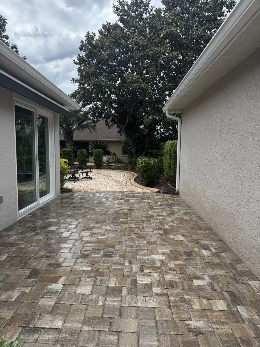 Wide paver path running between two wings of an Ocala house and opening onto a gravel sitting area