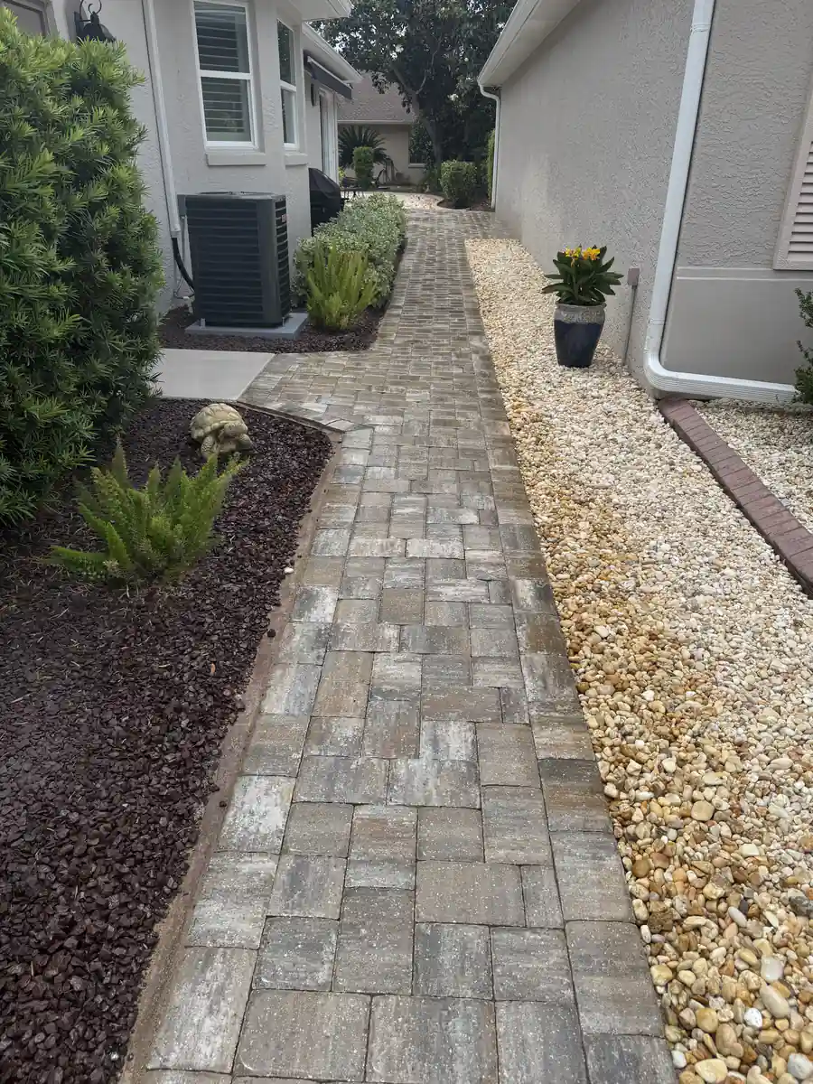 Blended tan and grey pavers leading along an Ocala side yard past the air conditioner